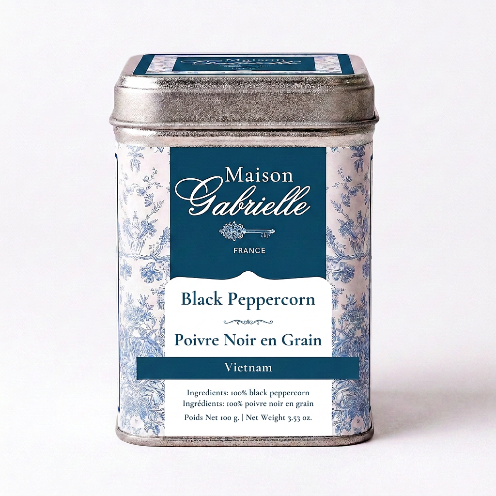 A metal tin of Maison Gabrielle Black Peppercorn (Poivre Noir en Grain) from Vietnam, featuring a blue and white floral pattern with a dark blue label.