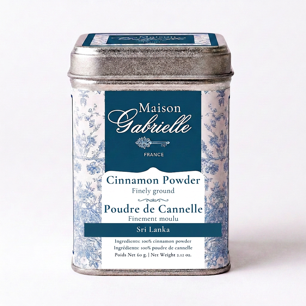 A metal tin of Maison Gabrielle Sri Lanka cinnamon powder, featuring a blue and white floral patterned label with a dark blue central panel.