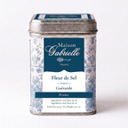 A metal tin of Maison Gabrielle FLeur de Sel from France, featuring a blue and white floral pattern with a dark blue label, set against a plain white background.