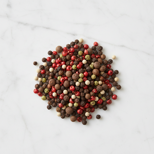 Maison Gabrielle 5 Peppercorn Blend with a Touch of Allspice Piled on a White Marble Surface for Gourmet Seasoning and Recipes