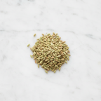 Overhead view of a mound of premium whole fennel seeds from Maison Gabrielle on a bright white marble surface, highlighting the spice's natural green and golden tones and ribbed texture.