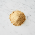 Premium Ground Ginger Powder by Maison Gabrielle, Artfully Piled on White Marble with Even, Soft Lighting to Highlight its Rich Golden Color and Fine Artisanal Texture