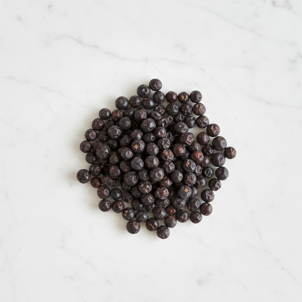 Professional Shot of Maison Gabrielle Dried Juniper Berries Arranged on a White Marble Surface, Highlighting the Deep Color and Quality of this Artisanal Botanical