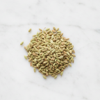 Top-Down Perspective of Maison Gabrielle Premium Whole Fennel Seeds on a Bright White Marble Counter, Showcasing the Natural Greenish-Gold Hue and Ribbed Texture of the Artisanal Spice