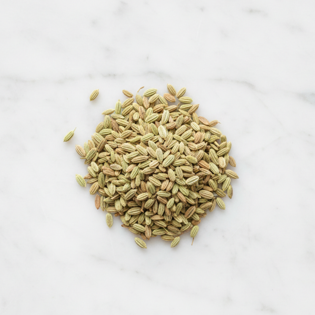 Top-Down Perspective of Maison Gabrielle Premium Whole Fennel Seeds on a Bright White Marble Counter, Showcasing the Natural Greenish-Gold Hue and Ribbed Texture of the Artisanal Spice