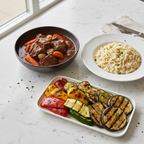Maison Gabrielle Beef Stew (Boeuf Bourguignon) with Carrots, Creamy Cheese Risotto Garnished with Parsley, and Grilled Vegetables on a White Marble Surface